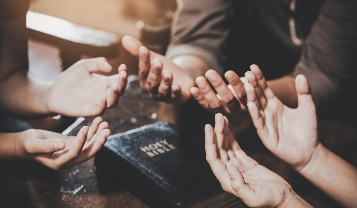 Group gathered in prayer around a Bible